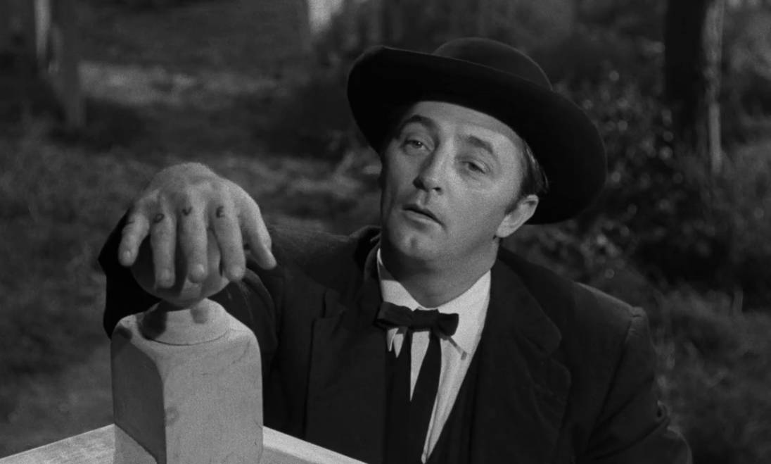 Cinematic Confluence: A Profound Still of Robert Mitchum from "Night of the Hunter" Wallpaper