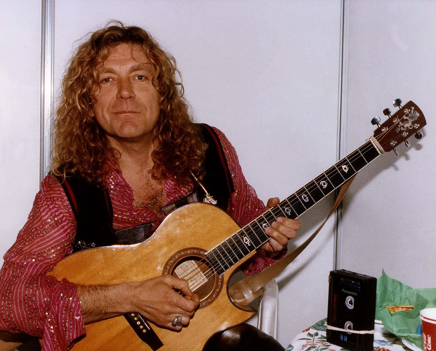 a man with long hair holding an acoustic guitar