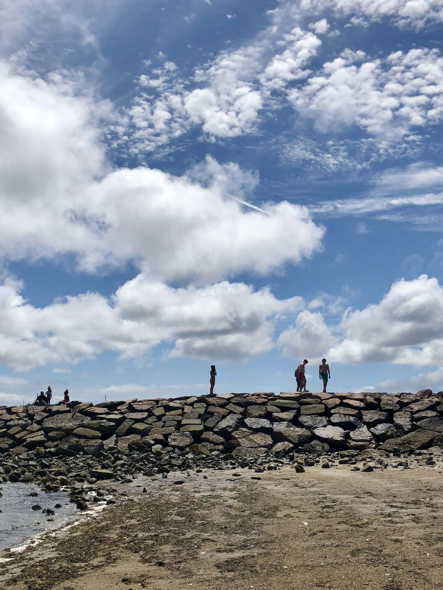 Rocky Beach Promenade Under Cloudy Sky Wallpaper