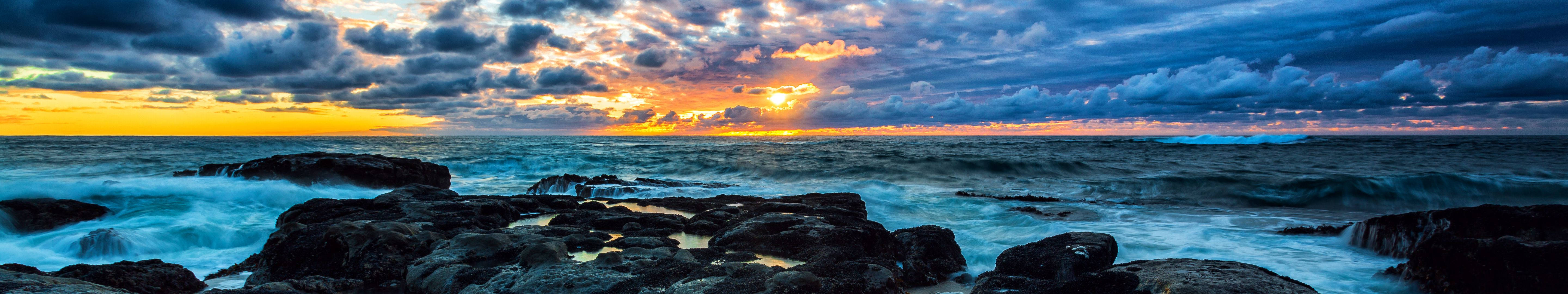 Watch the sunrise from a rocky beach Wallpaper