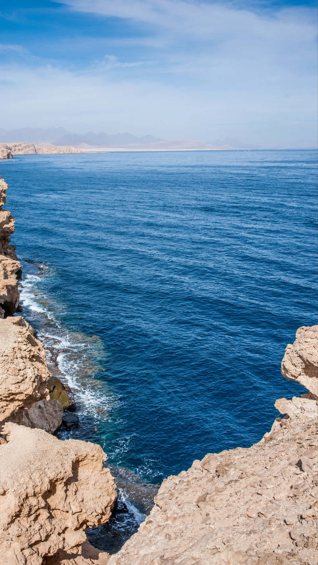 Rocky Cliff Overlooking Blue Ocean.jpg Wallpaper