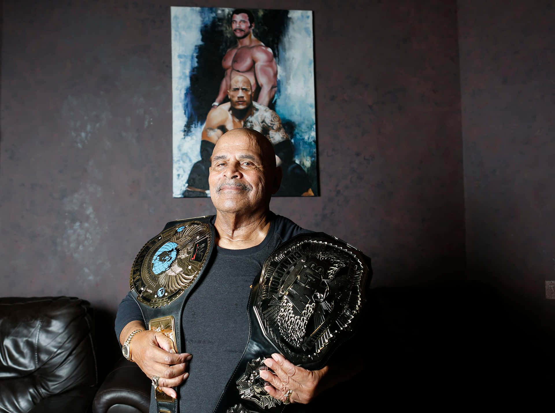 Rocky Johnson holder to Champion bælter imod en Mursten væg Wallpaper