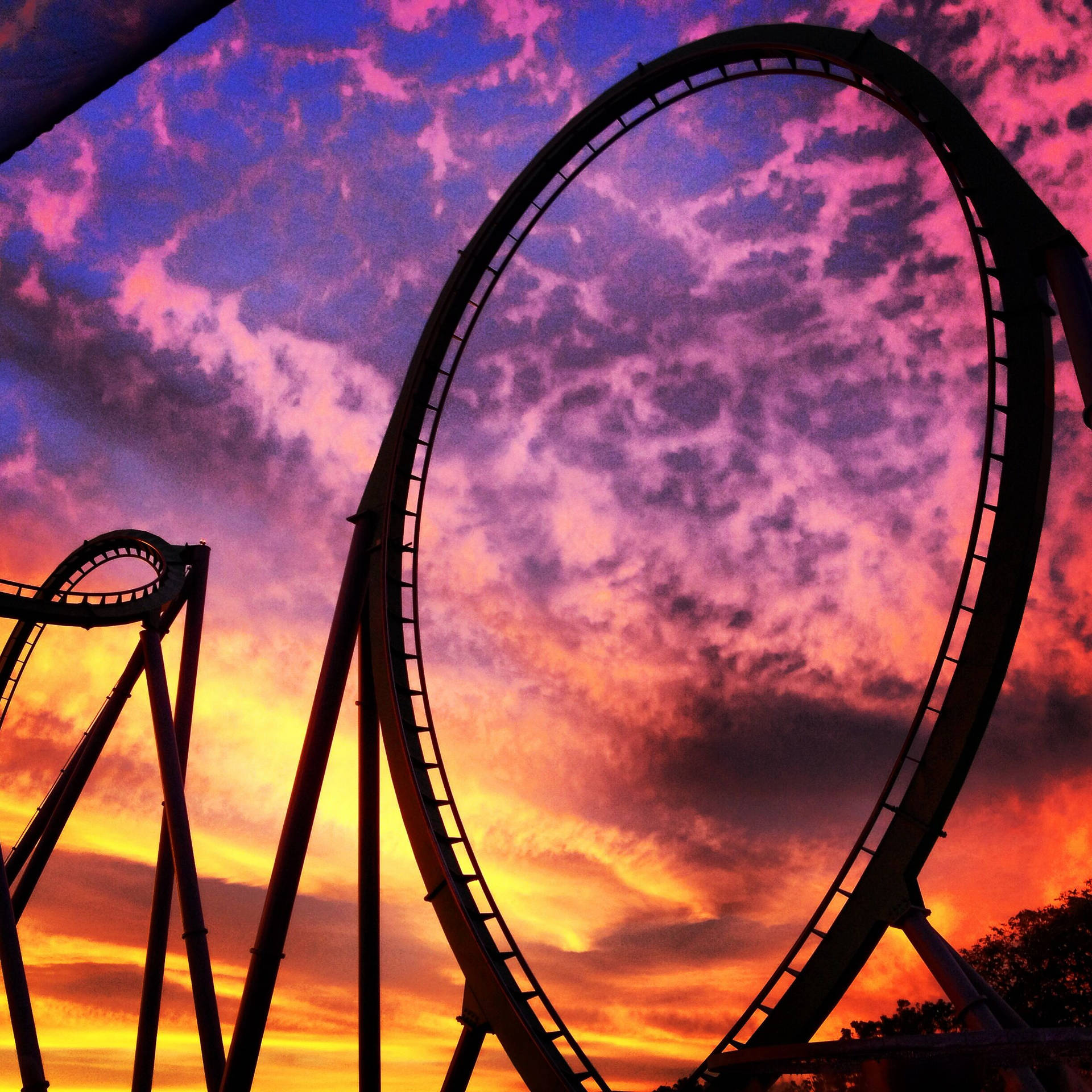 High-Flying Thrill on a Roller Coaster amidst Vibrant Sunset Wallpaper