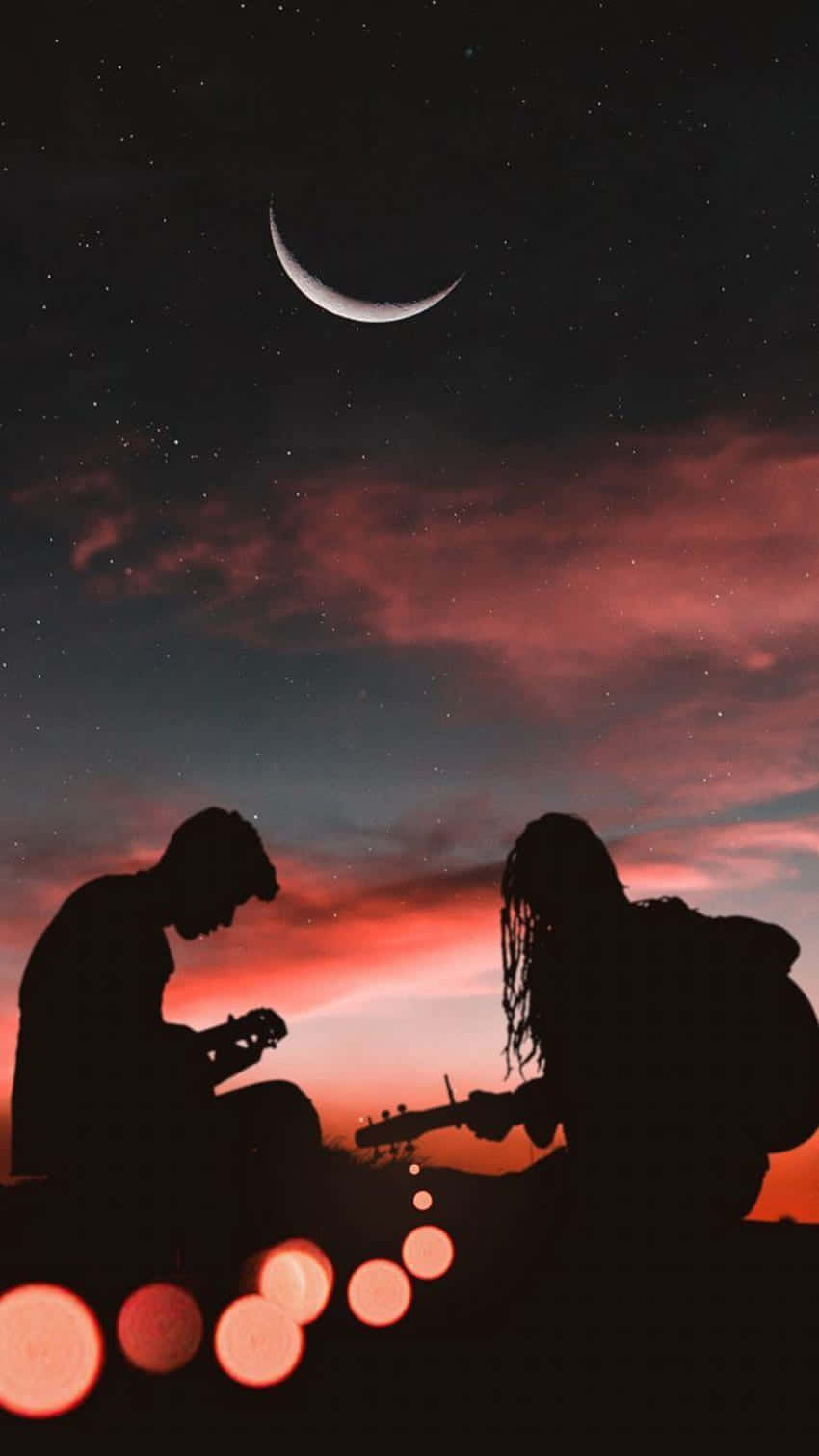 Paar,das Unter Dem Romantischen Hintergrund Eines Twilit Himmels Gitarre Spielt