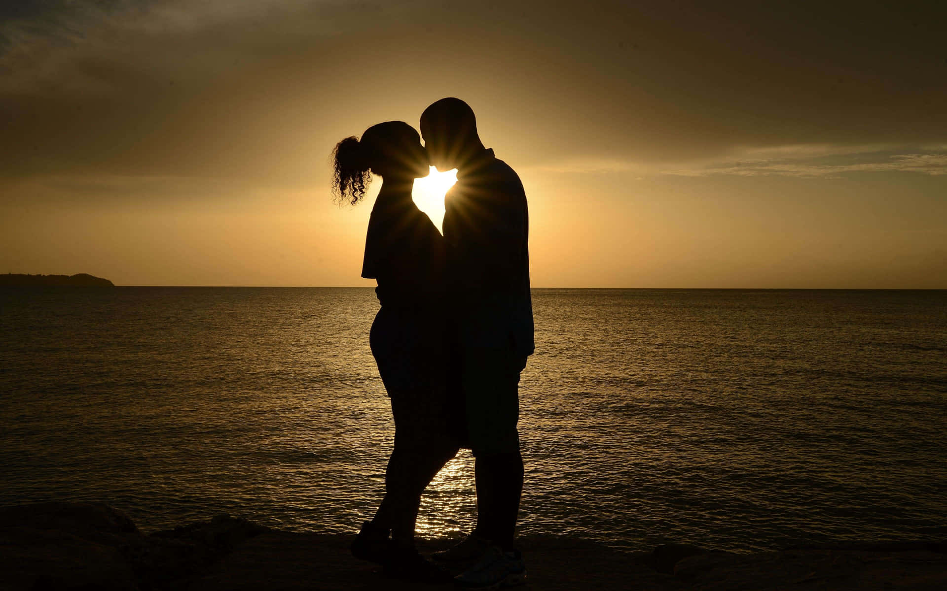 A romantic couple cuddling beside a beautiful sunset