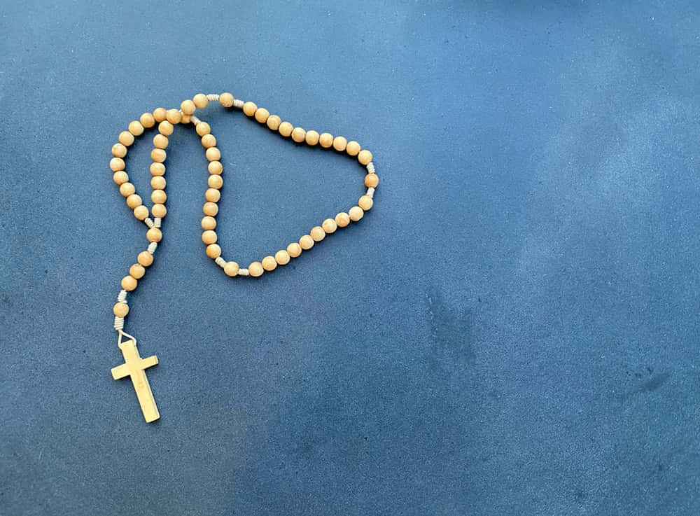 Wooden Rosary On A Matte Blue Surface Picture