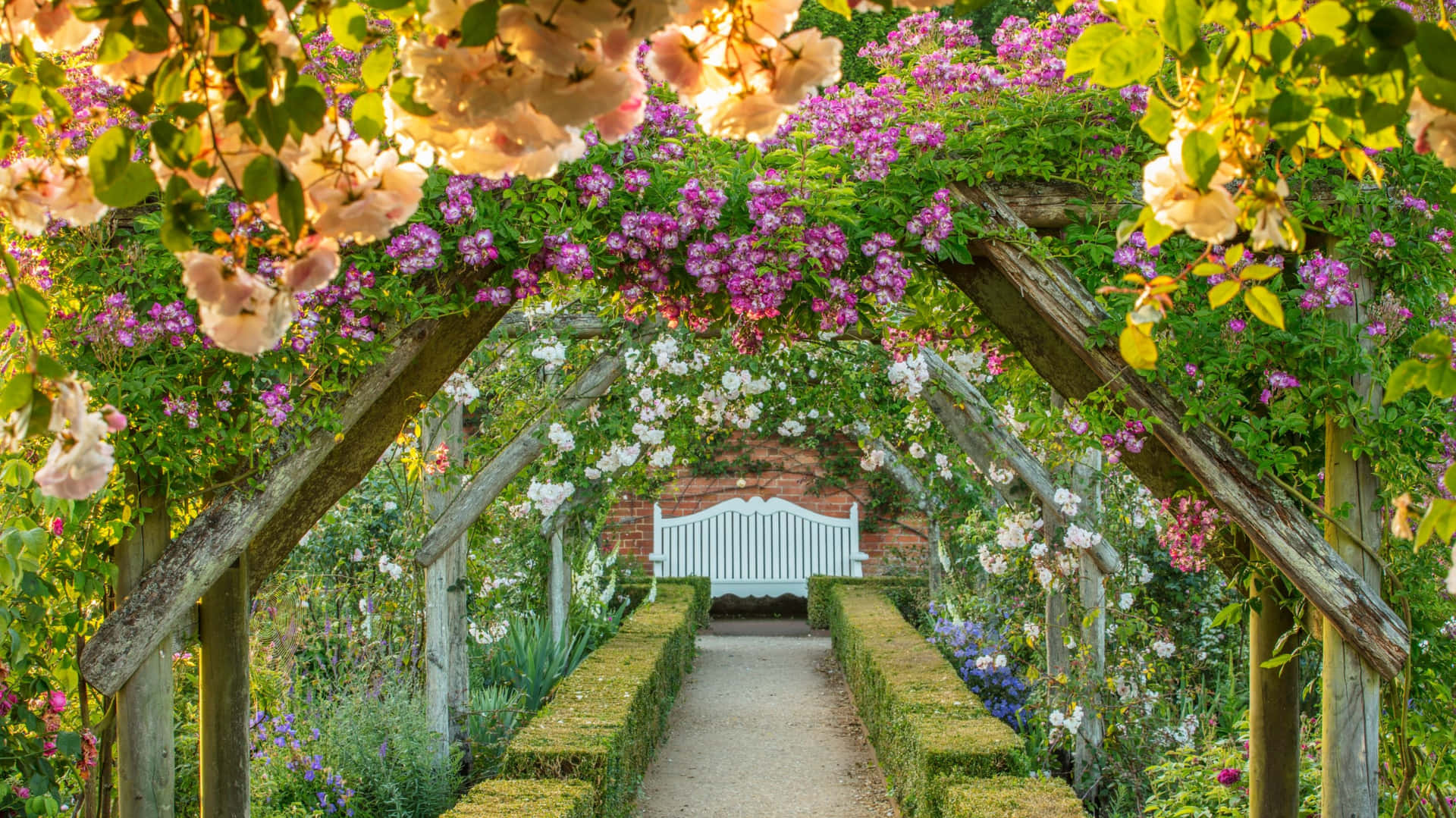 A Pathway With Flowers And A Wooden Archway