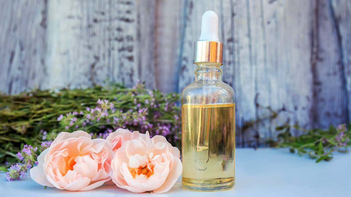 Luxurious Rose Oil in Glass Dropper Bottle with Fresh Blooming Roses Wallpaper