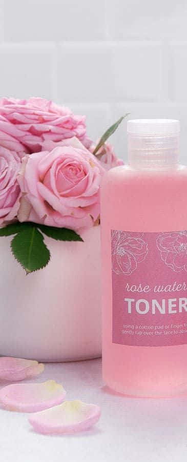 Luxurious rose oil in an elegant glass dropper bottle surrounded by bright red roses. Wallpaper