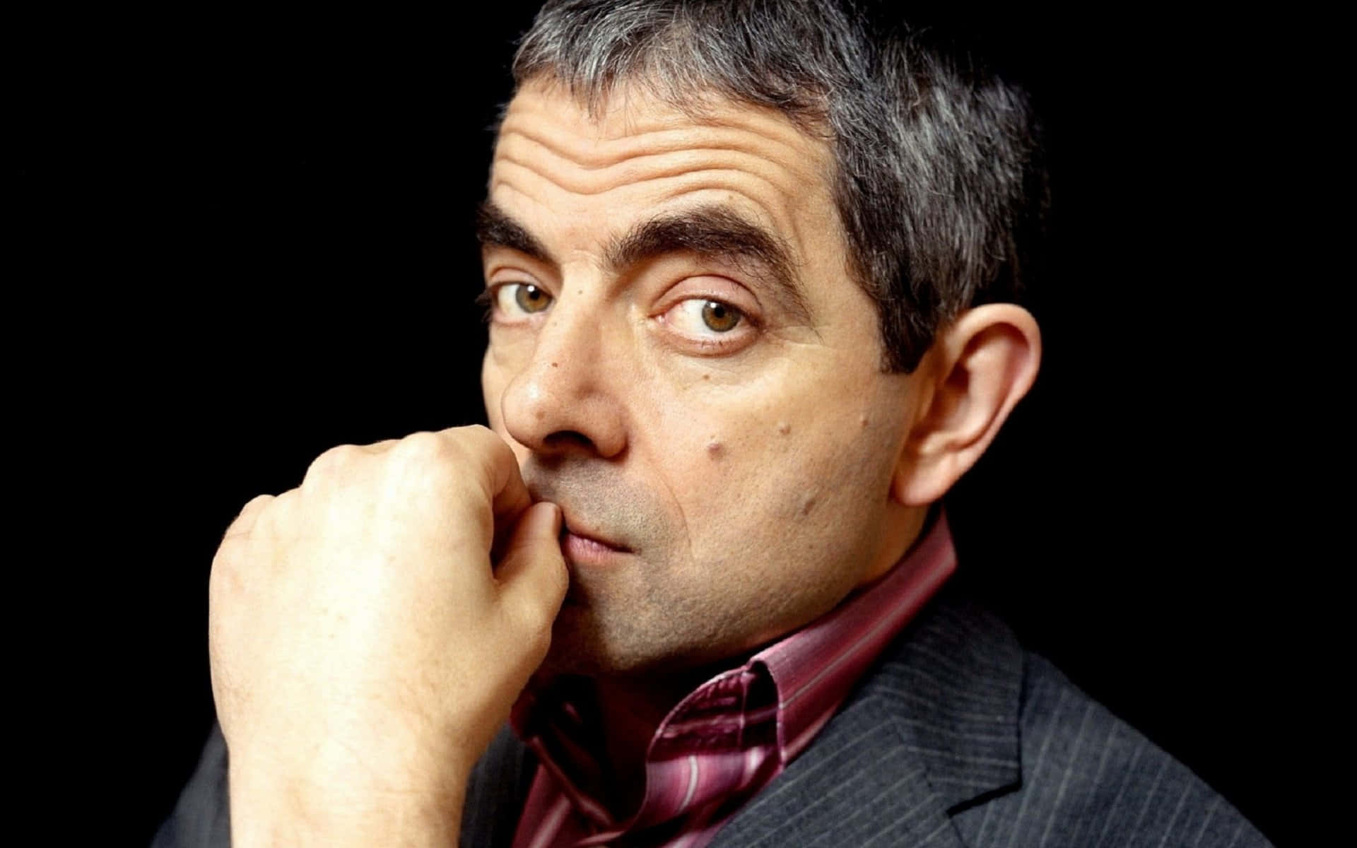 Iconic Actor Rowan Atkinson Posing on Red Background Wallpaper