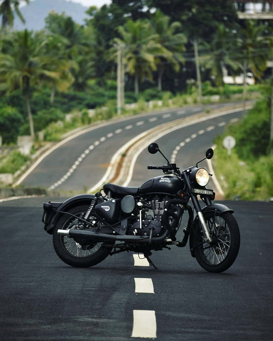 A Black Motorcycle Parked On A Road Near Palm Trees