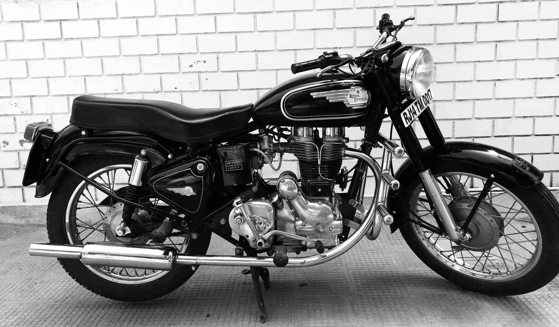 A Black And White Photo Of A Motorcycle Parked In Front Of A Brick Wall