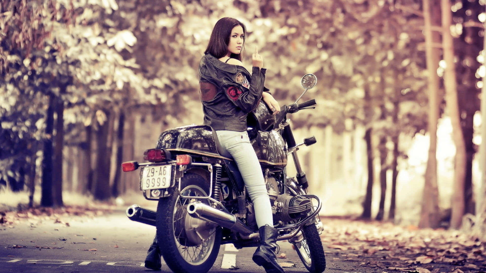 A Woman Sitting On A Motorcycle In The Woods Wallpaper