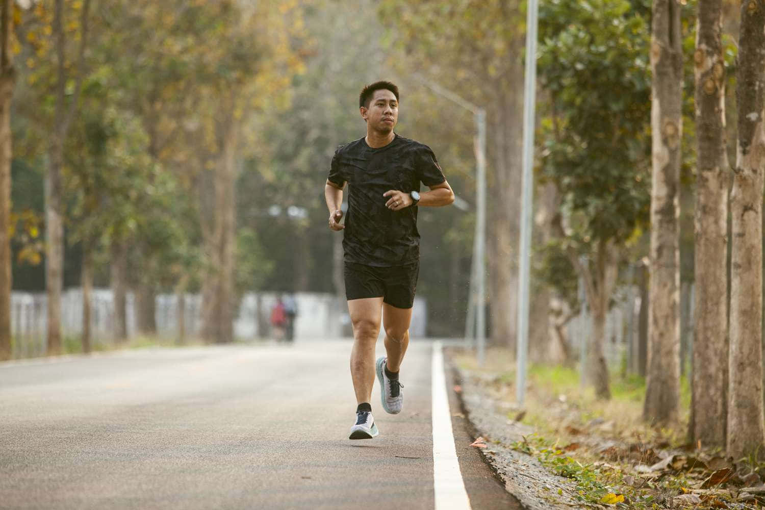 A Man Is Running On A Road In The Forest