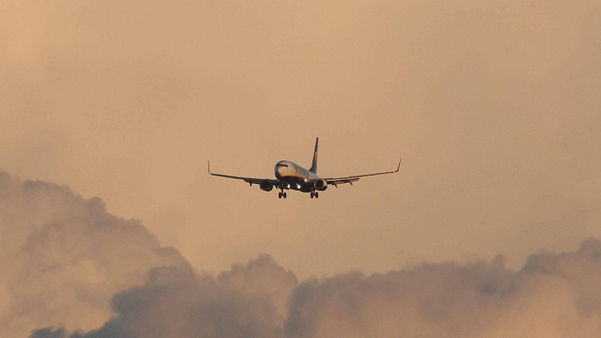 Aviónde Ryanair Sobre Un Cielo Naranja Y Nublado. Fondo de pantalla