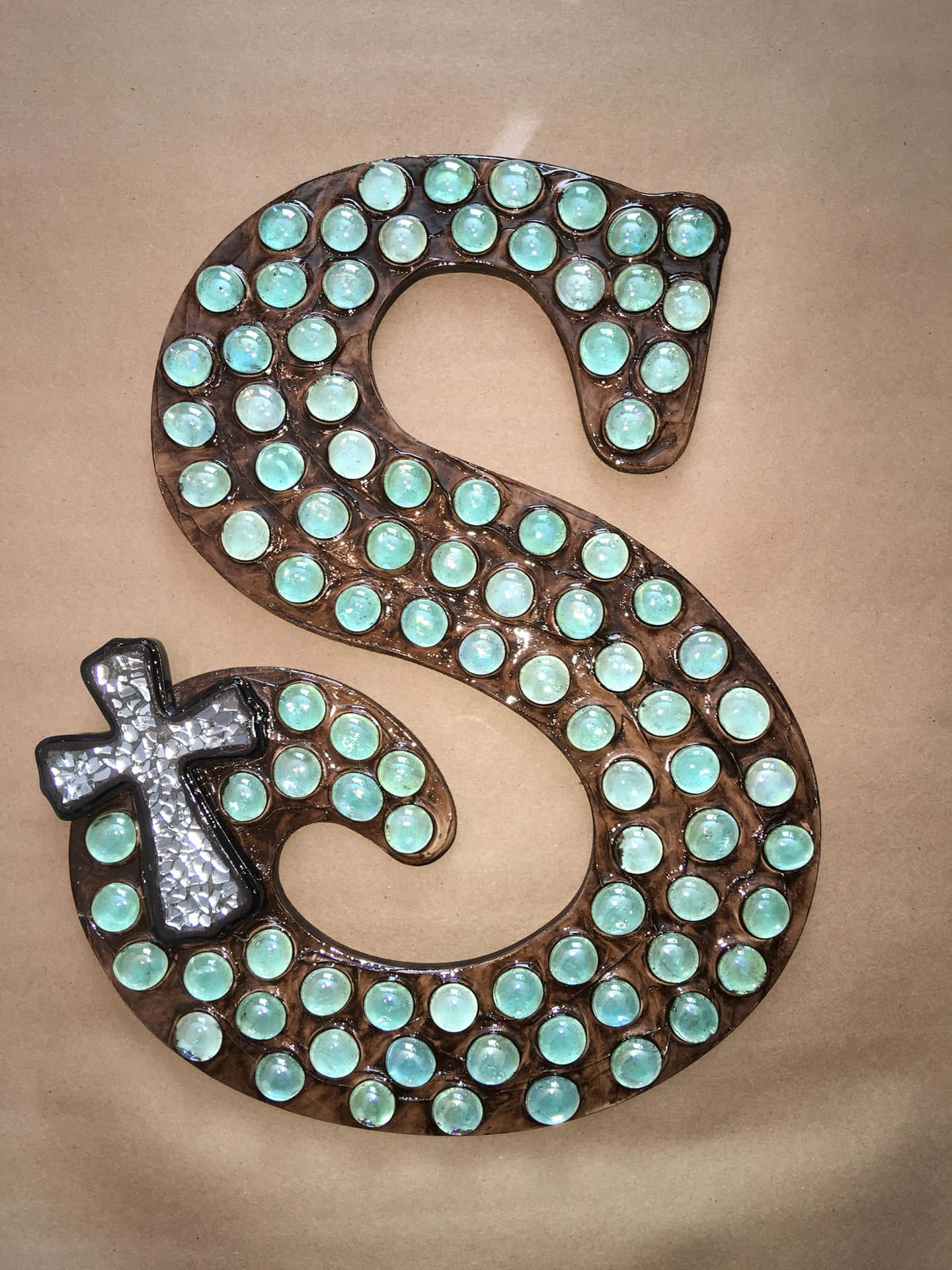 A Wooden Letter S With Green And Silver Beads Wallpaper