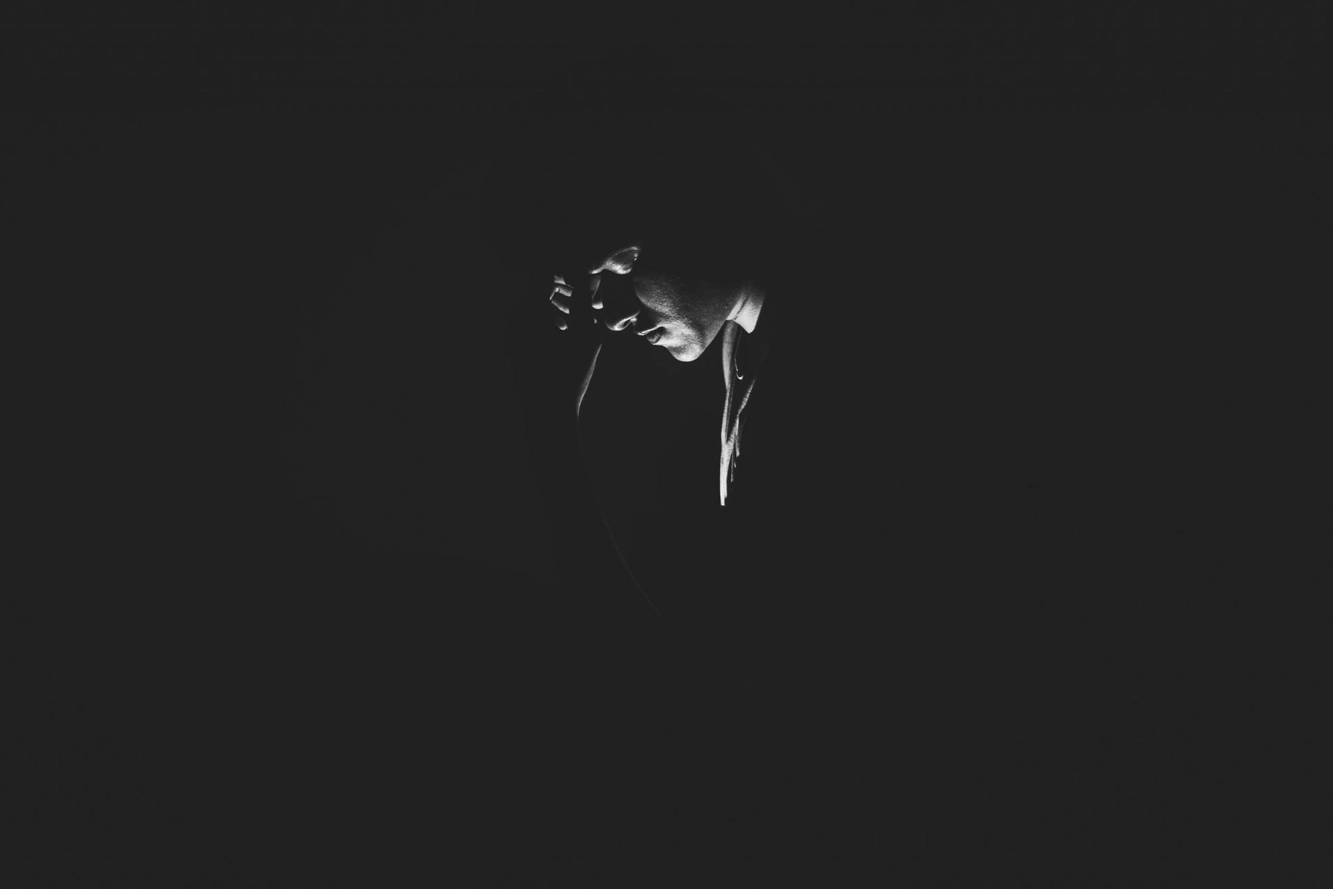 Et sort og hvidt fotografi af en person i mørke. Wallpaper