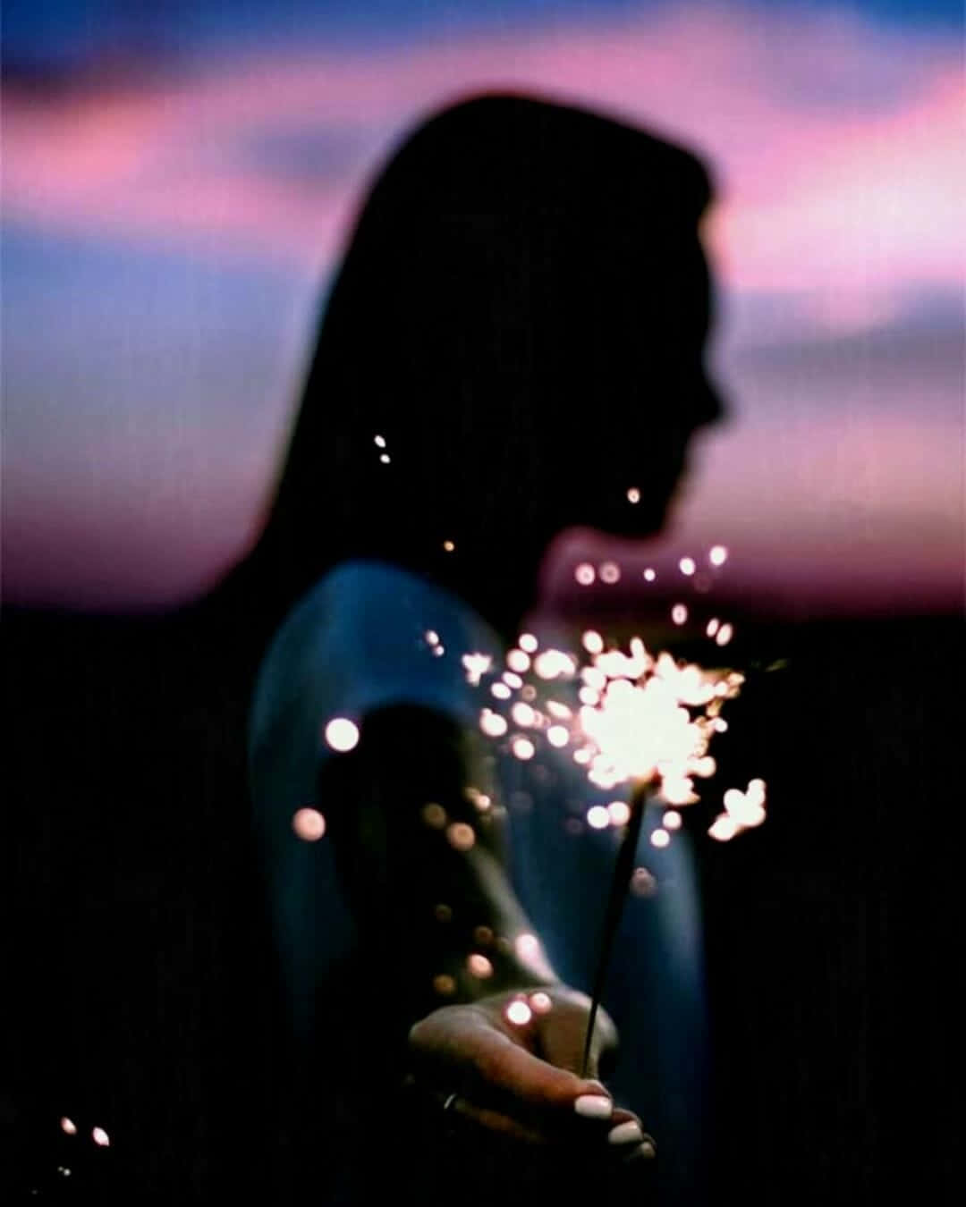 A Silhouette Of A Woman Holding A Sparkler Wallpaper