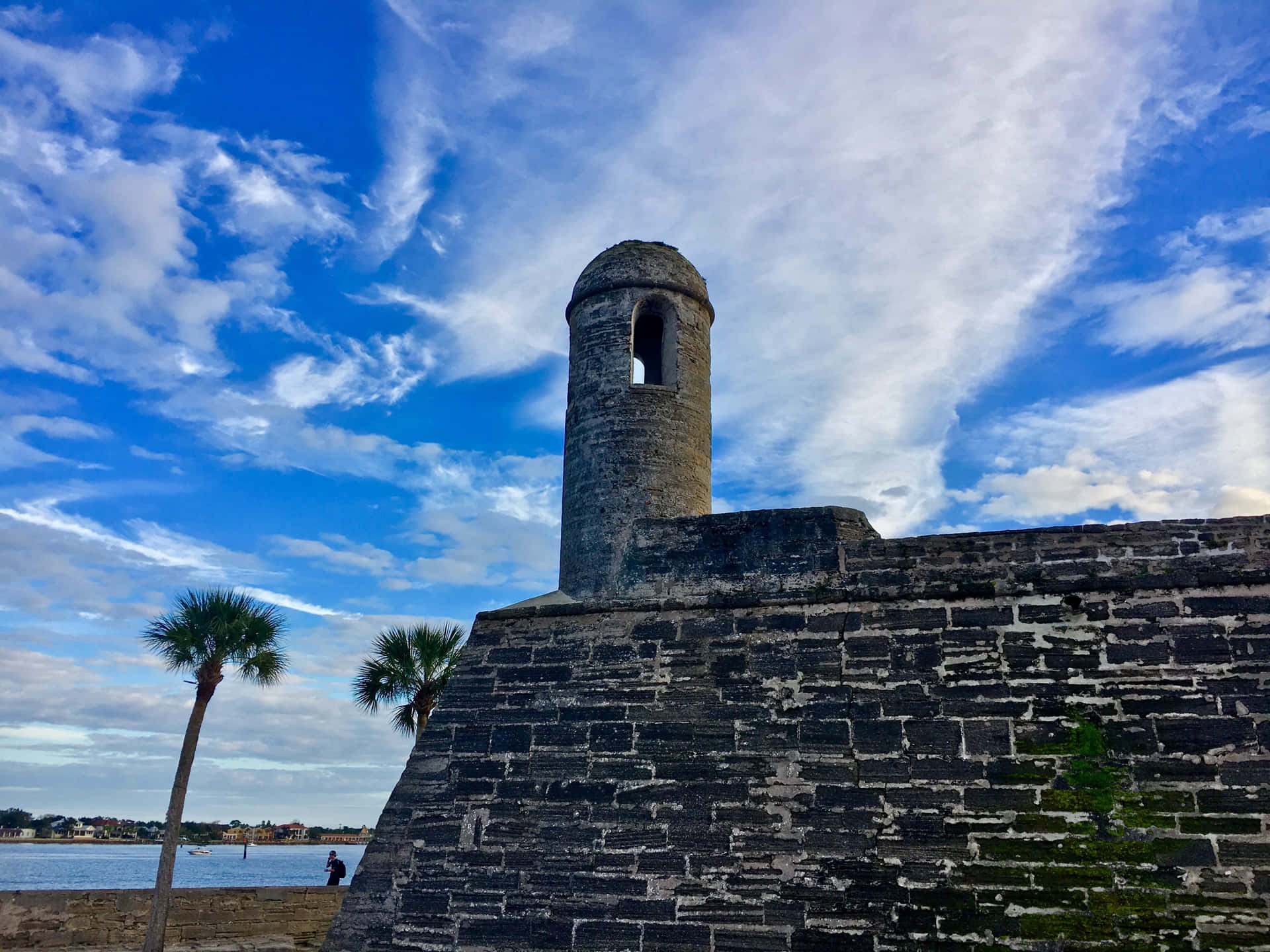 A Fortification Tower With A Clock Tower And Palm Trees