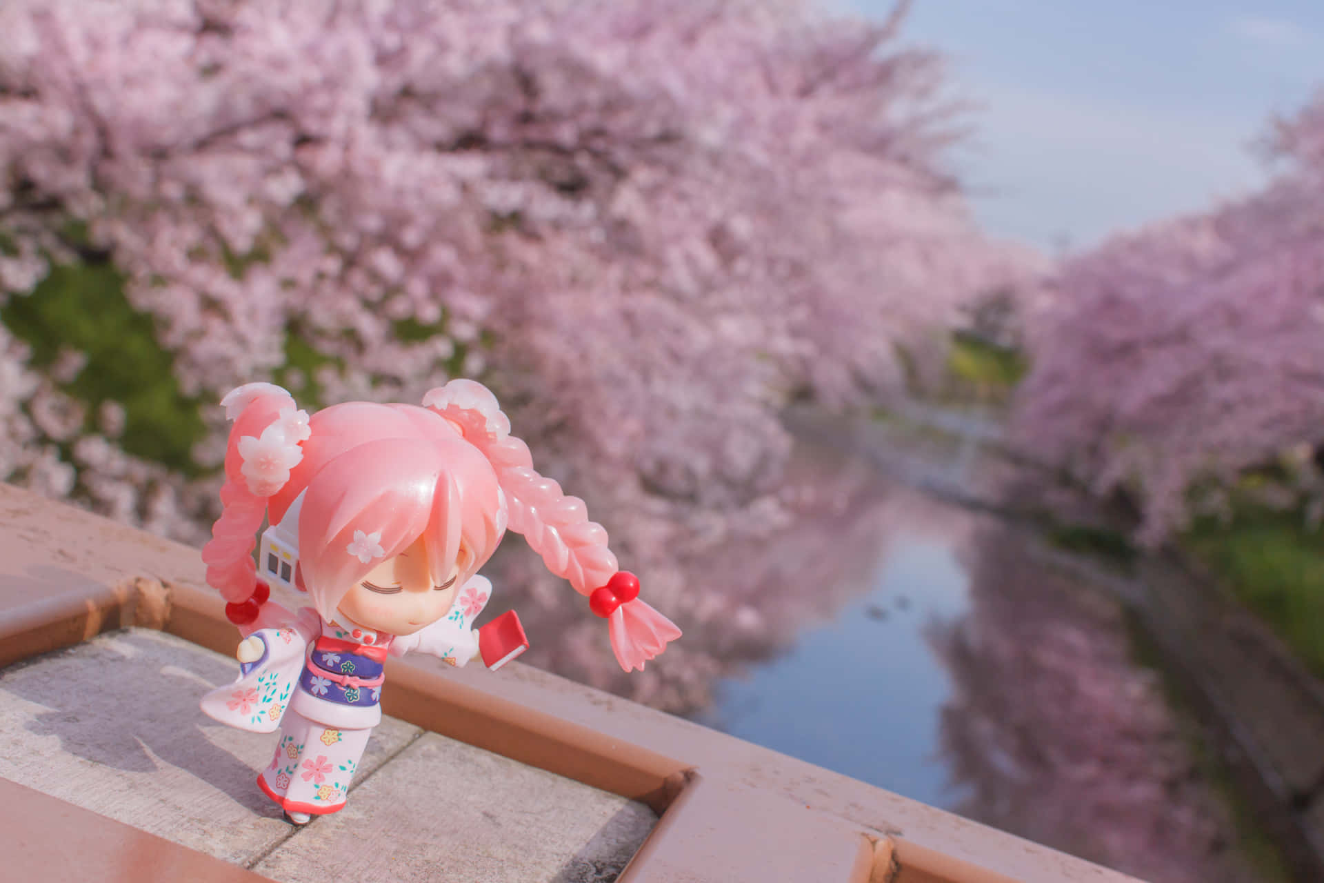 A Doll Standing On A Bridge Near A Cherry Blossom Tree Wallpaper