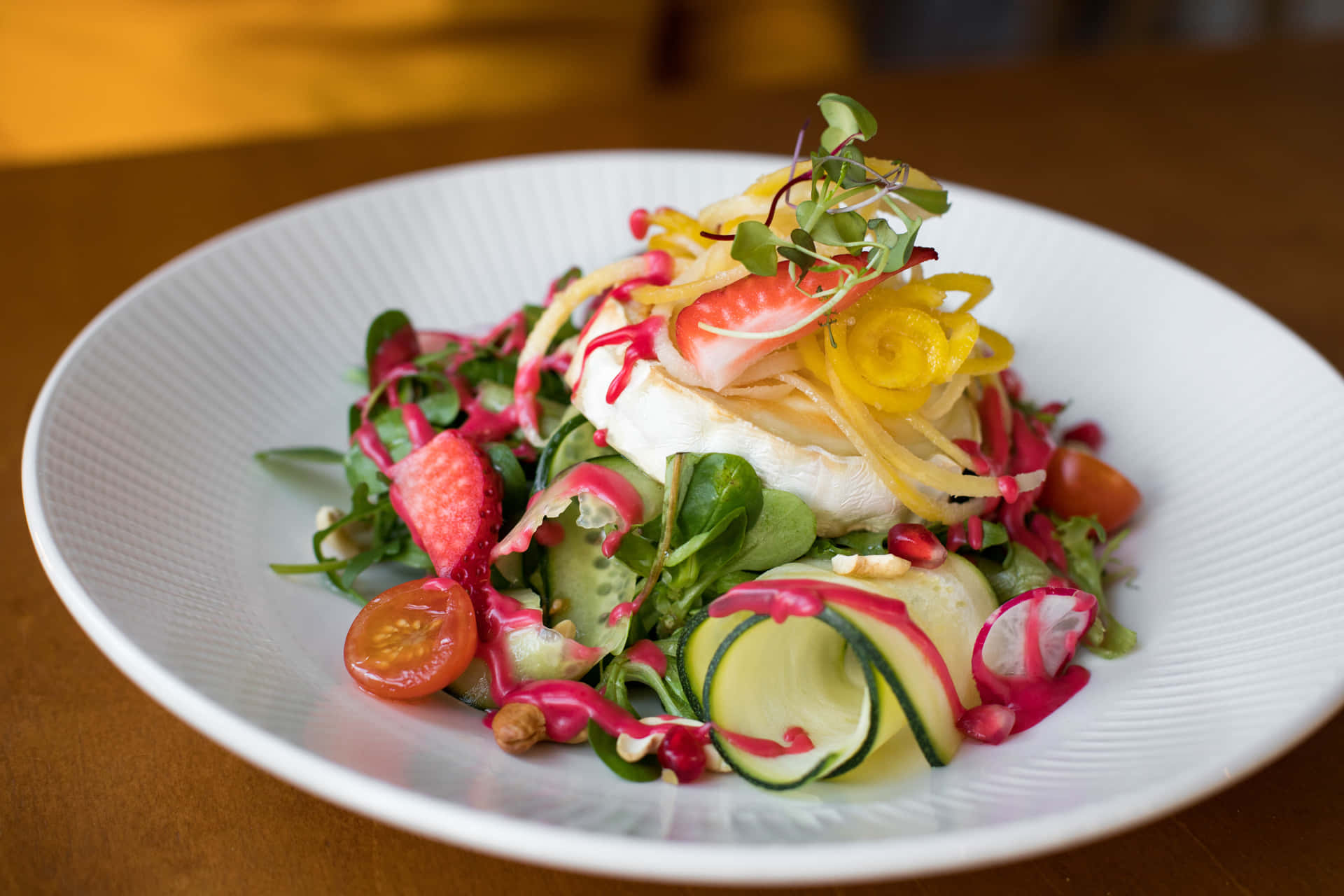 A colorful and flavorful salad made with fresh leafy greens, mandarin orange slices, strawberries, almonds and goat cheese crumbles.