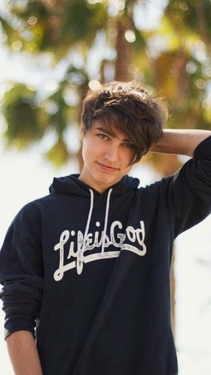 A Young Man Wearing A Black Hoodie And A Palm Tree Wallpaper