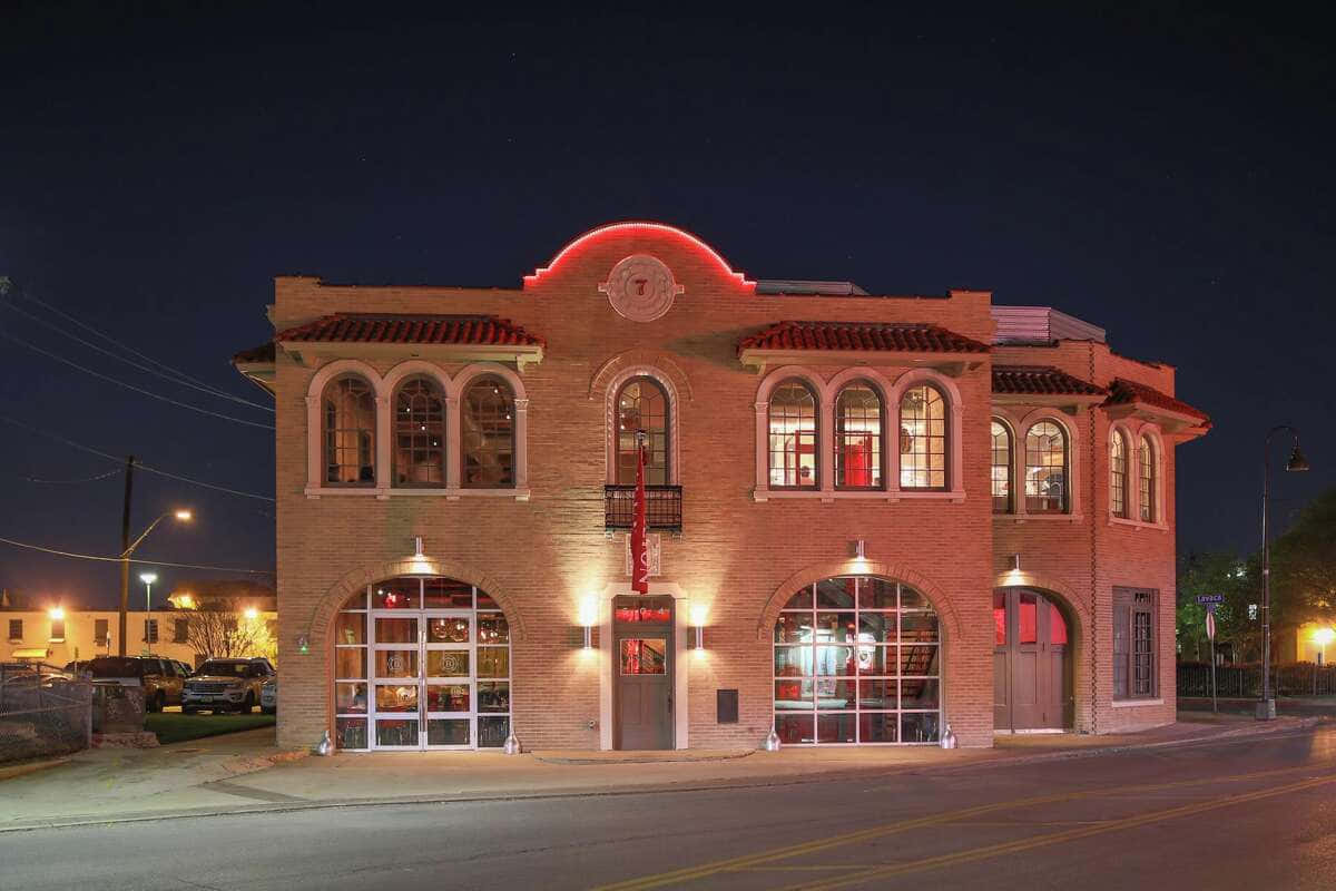 A Firehouse Building At Night With Lights On
