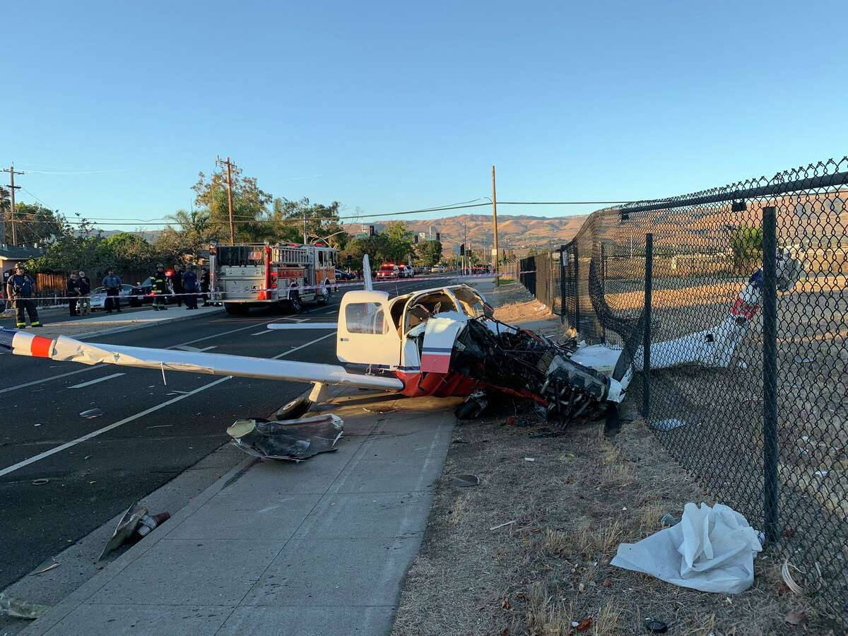 a small plane crashed into a fence near a road Wallpaper