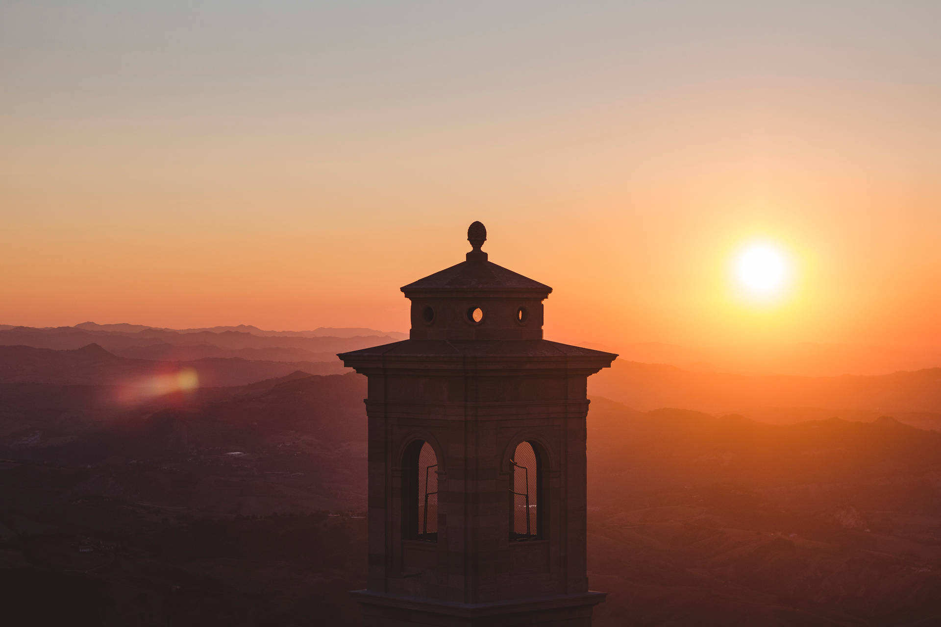 San Marino City Sunset – Et panorama af San Marinos bakker i et majsfarvet aftensky Wallpaper