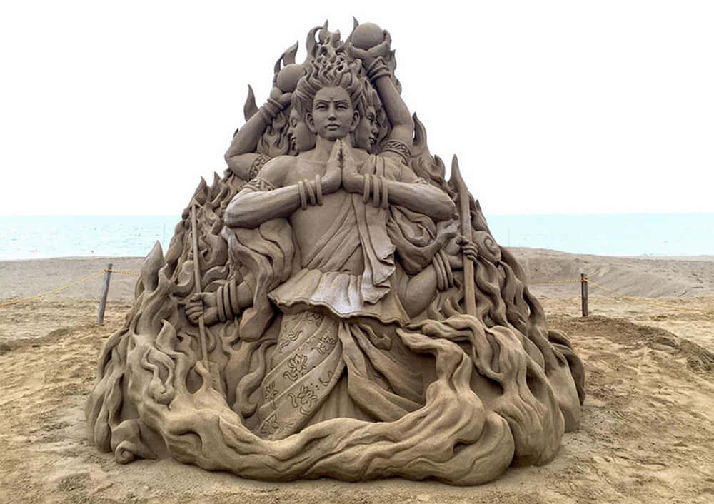 A Sand Sculpture Of A Buddha On The Beach
