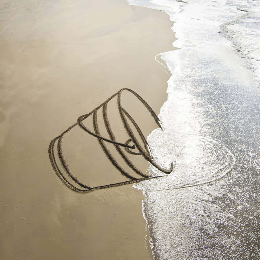 A Bucket Is Drawn In The Sand On The Beach