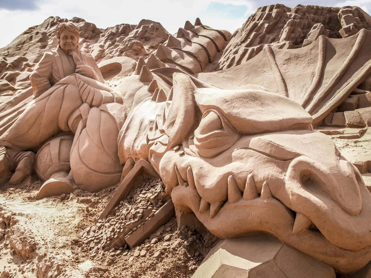 A Sand Sculpture Of A Dragon On A Beach