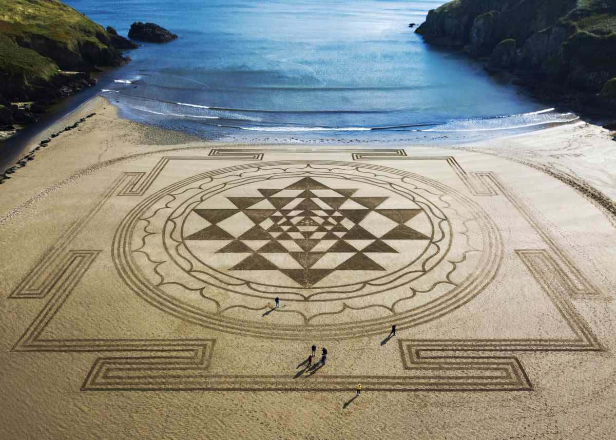 A Sand Drawing On The Beach With People Walking Around