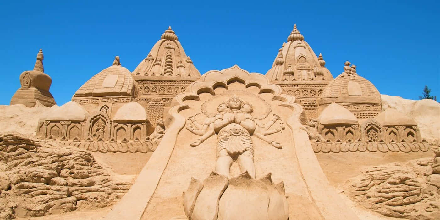 Sand Sculptures In A Desert With A Temple In The Background