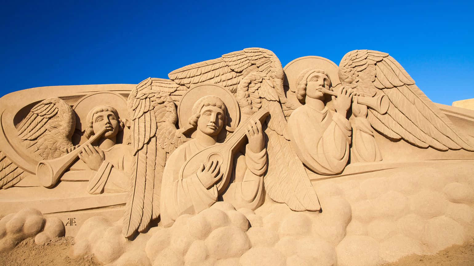 Sand Sculptures Of Angels And A Cross