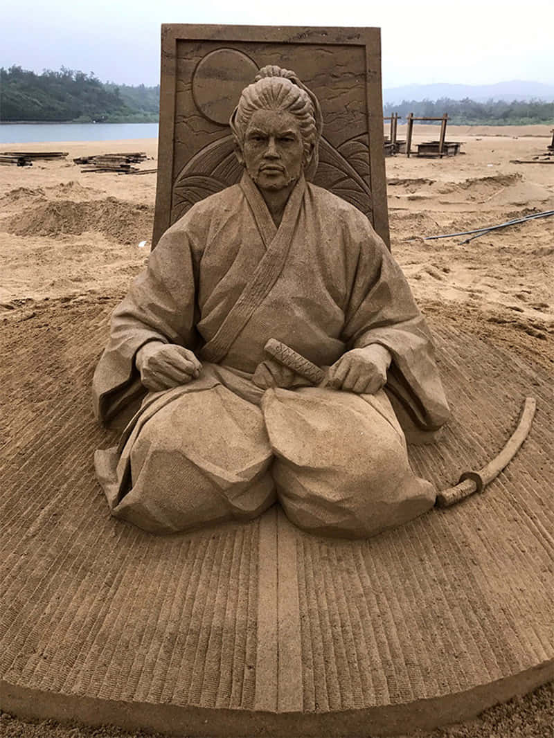 A Sand Sculpture Of A Man Sitting On A Chair