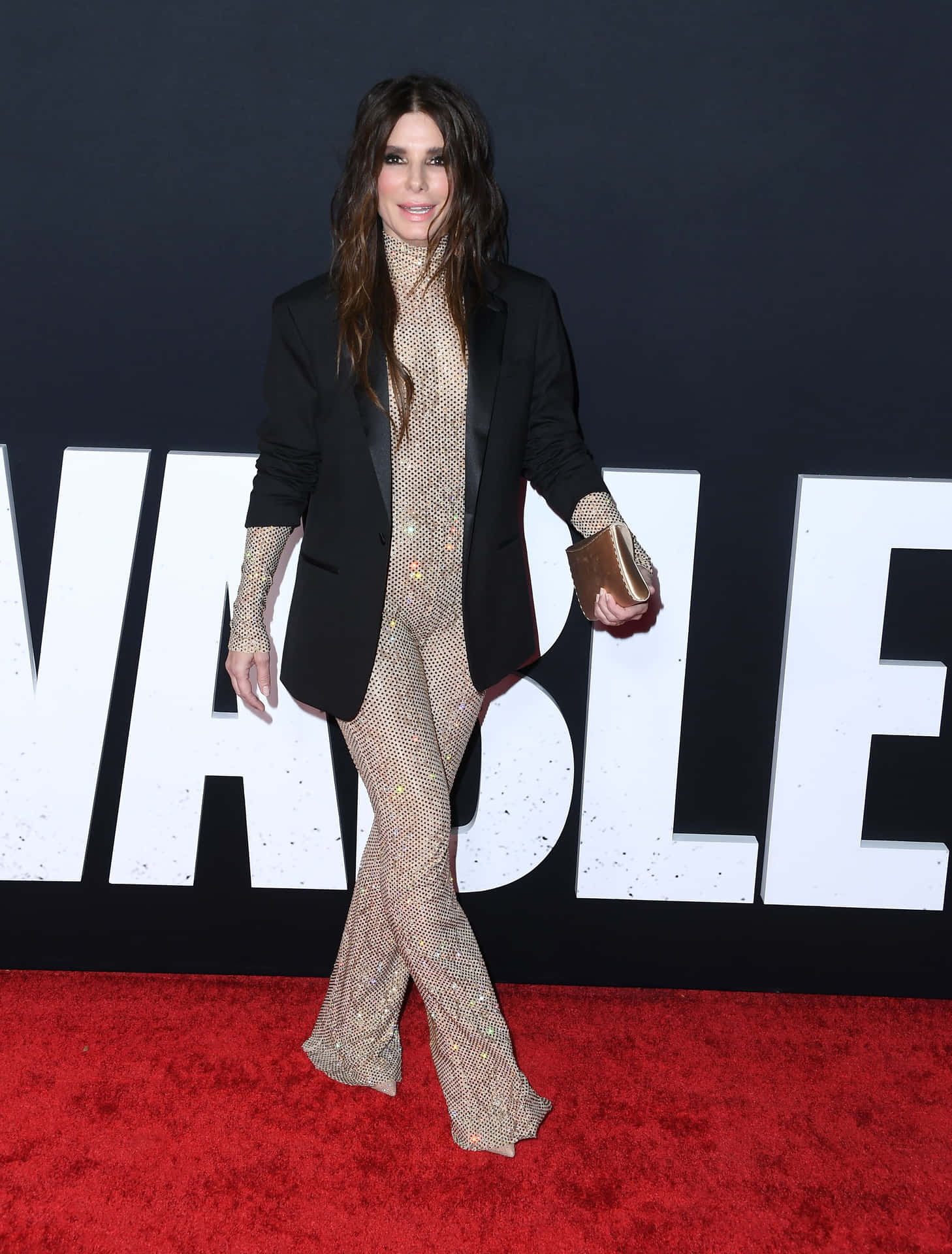 A Woman In A Black Suit And Gold Pants On A Red Carpet