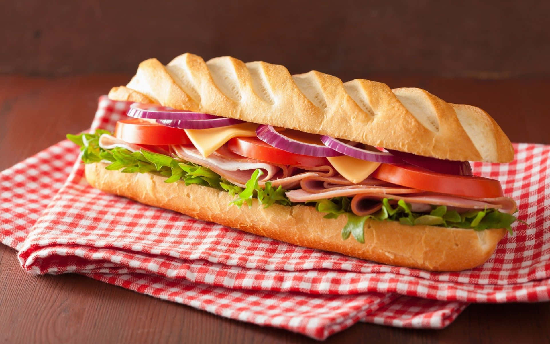 Unsándwich Con Carne, Queso Y Vegetales Sobre Una Servilleta De Cuadros