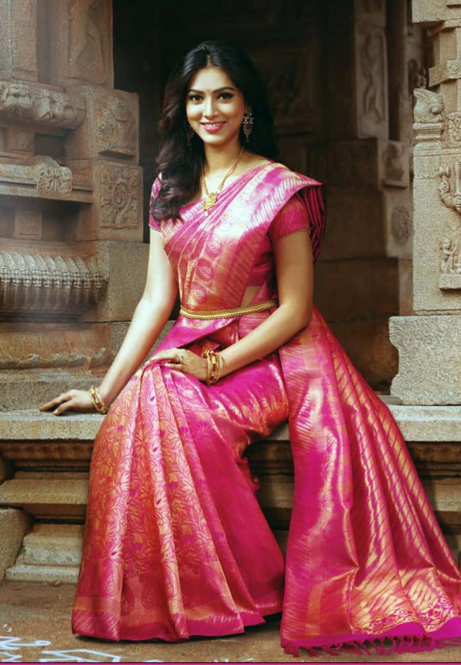 A Beautiful Woman In A Pink Sari Sitting On A Stone
