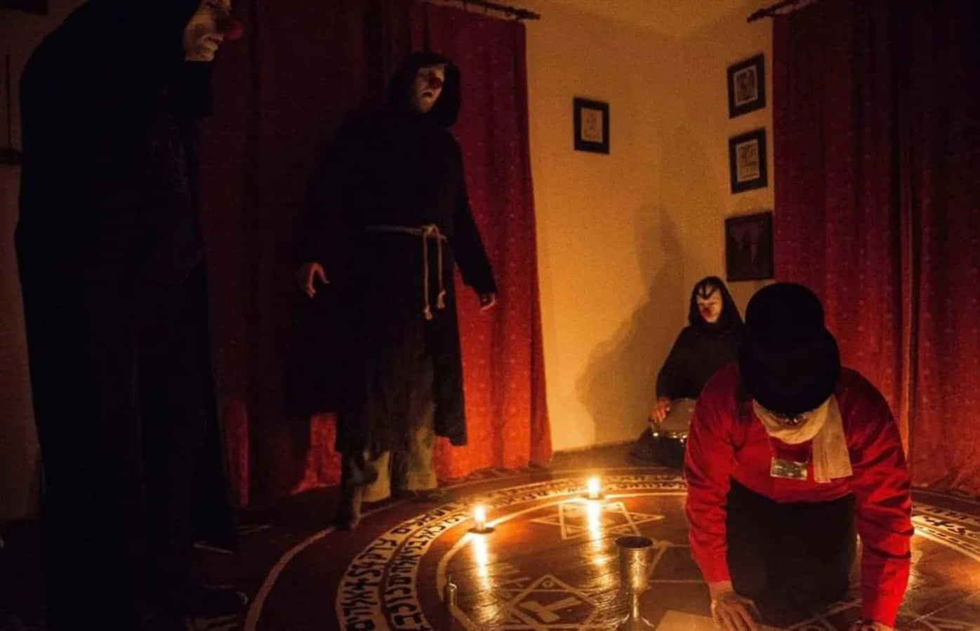 Einegruppe Von Personen In Schwarzen Gewändern Steht Um Eine Kerze Herum.