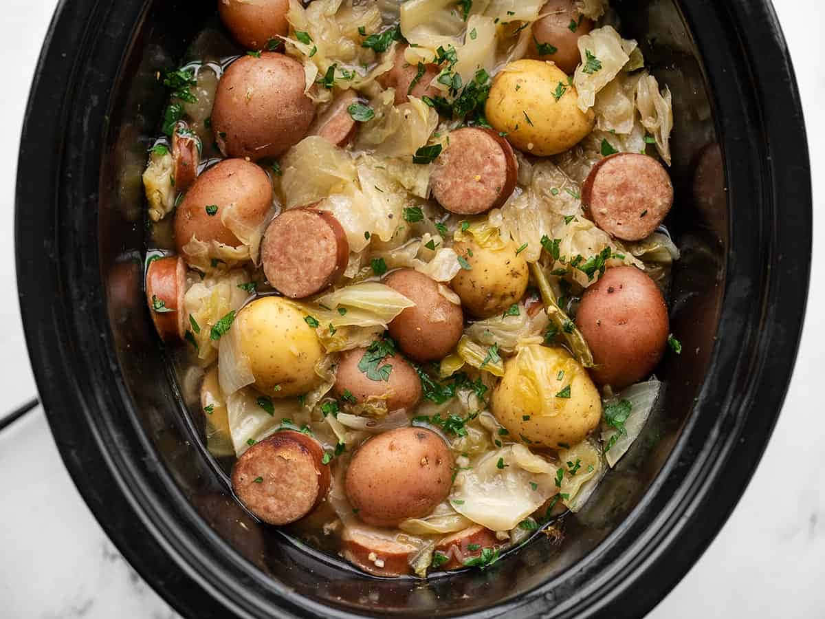 A Crock Pot Filled With Potatoes And Sausages