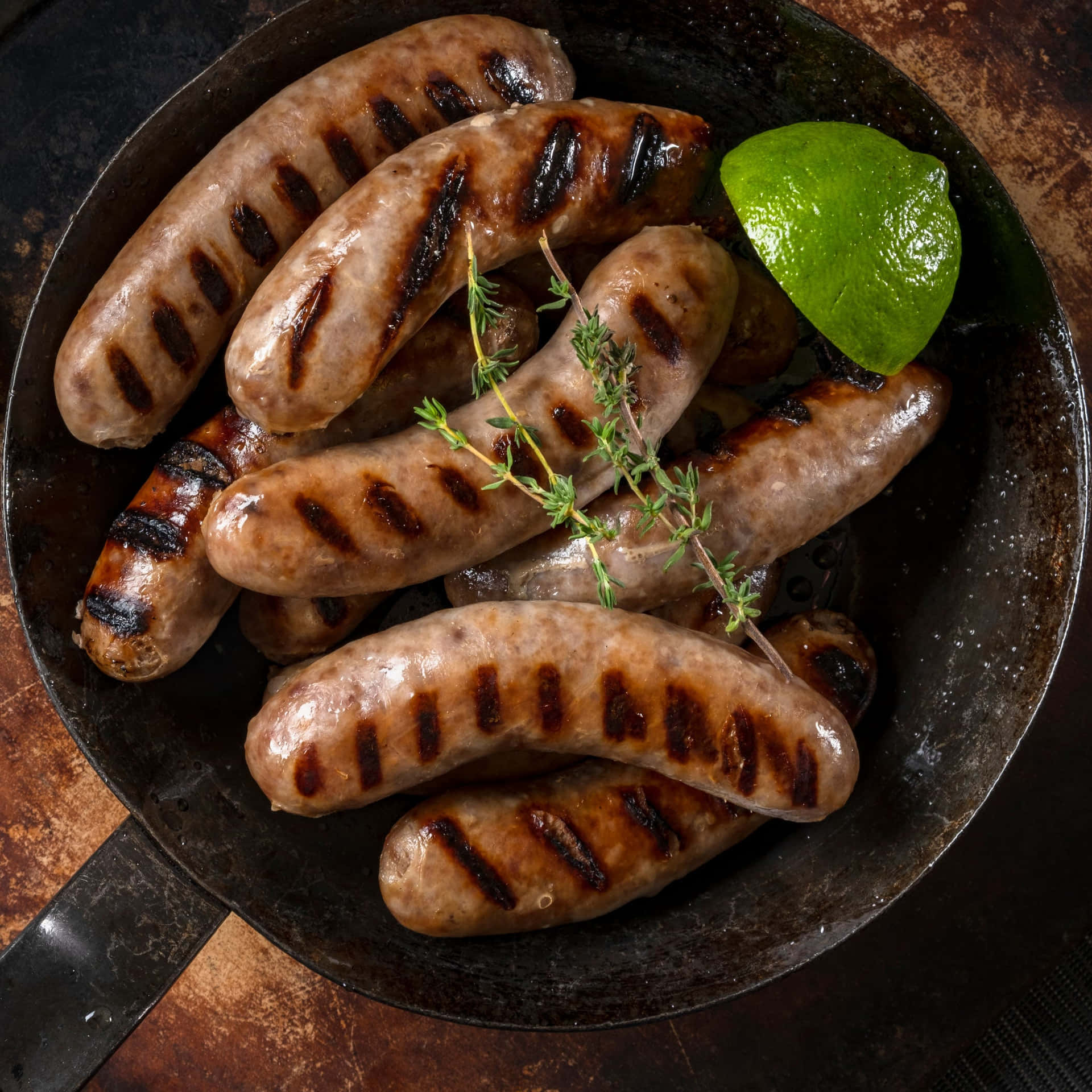 Grilled Sausages In A Skillet With Lime Wedges