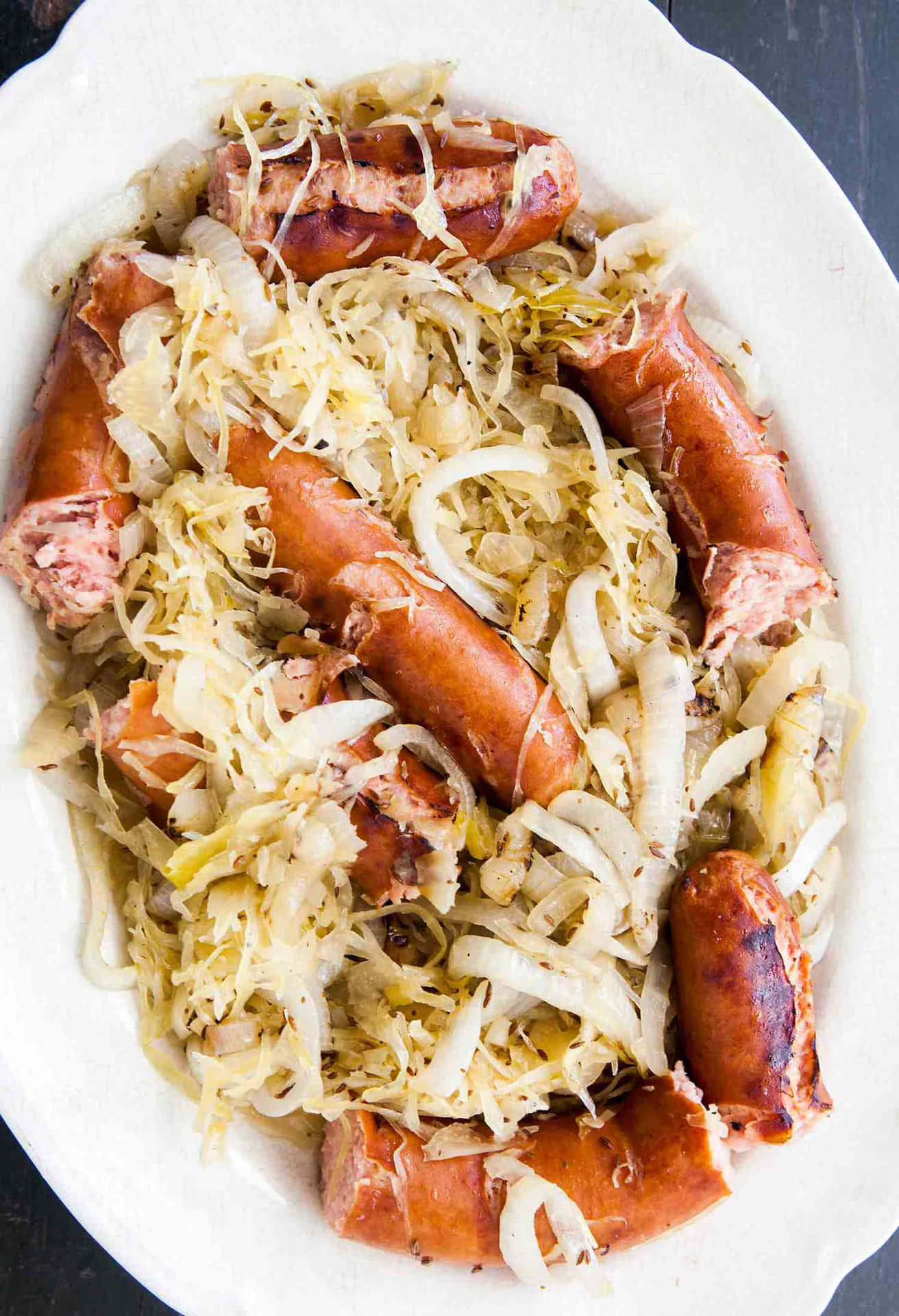 A White Plate With Sausages And Sauerkraut