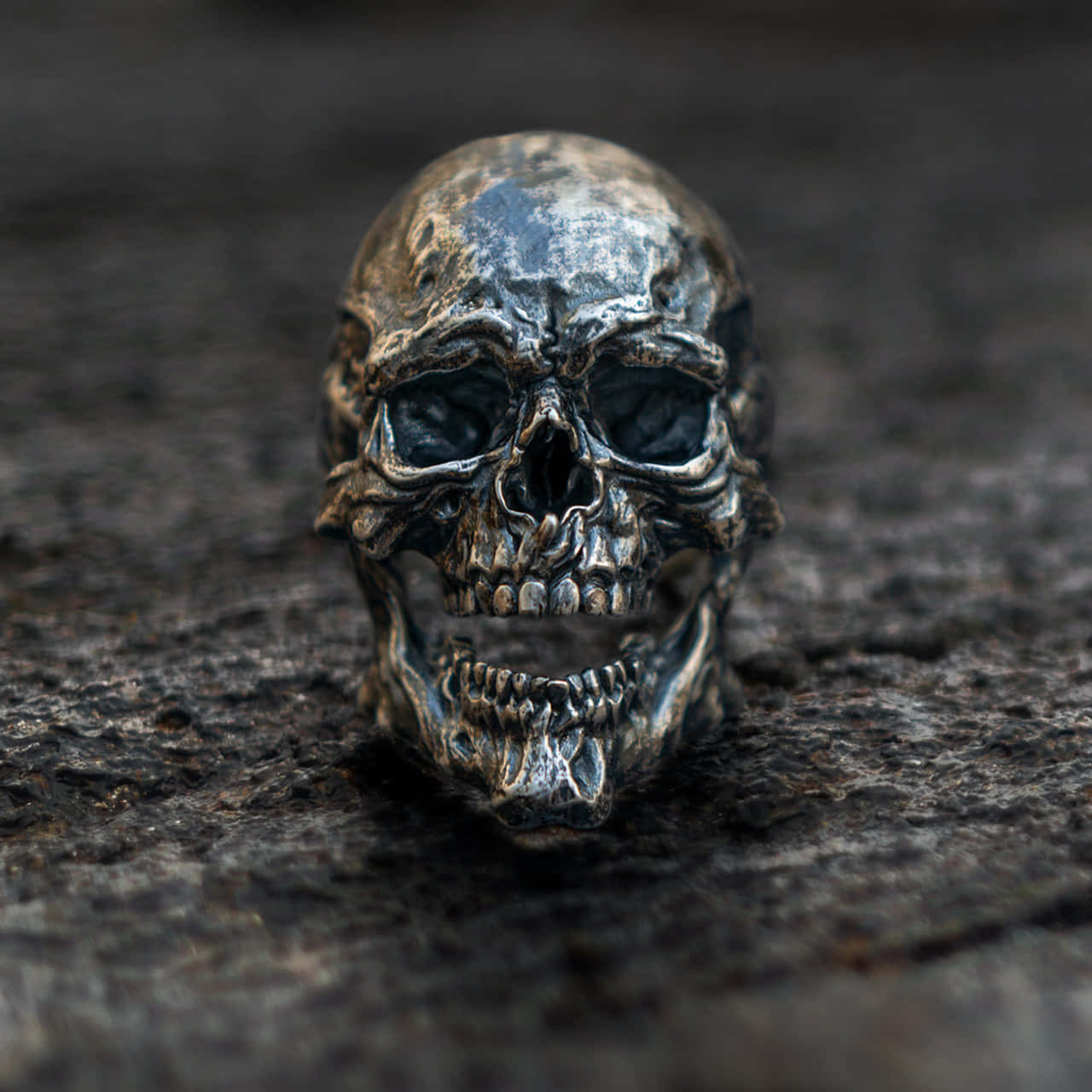 a silver skull ring on a wooden surface
