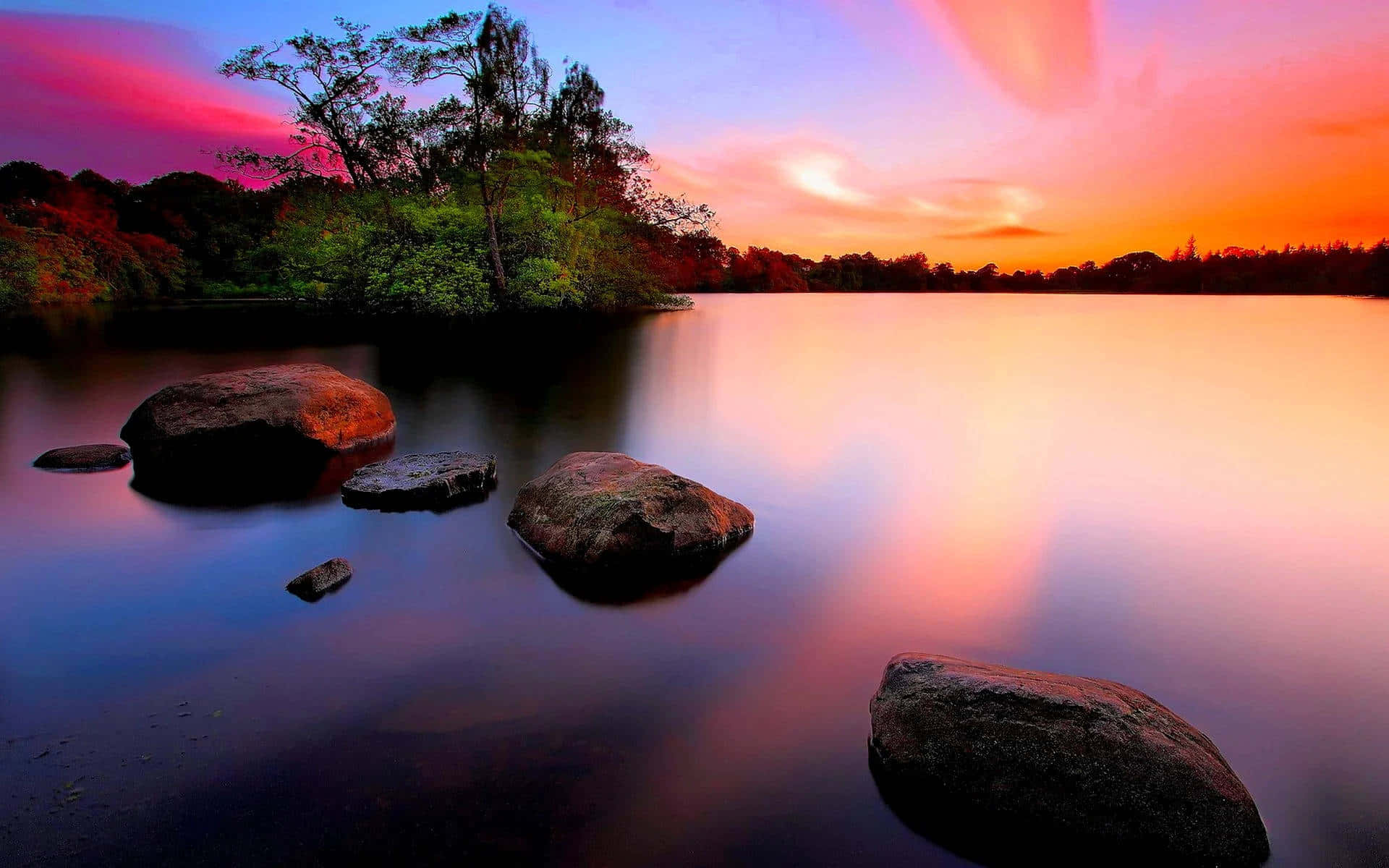 A Lake With Rocks And A Colorful Sunset