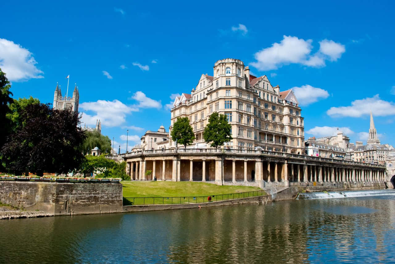 Scenic View Of The Historic City Of Bath, Uk Nestled Amidst Green Hills Under A Clear Blue Sky. Wallpaper