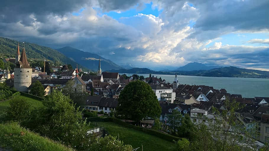 Scenic View Of Zug City By Night With The Snow-capped Mountains In The Backdrop Wallpaper