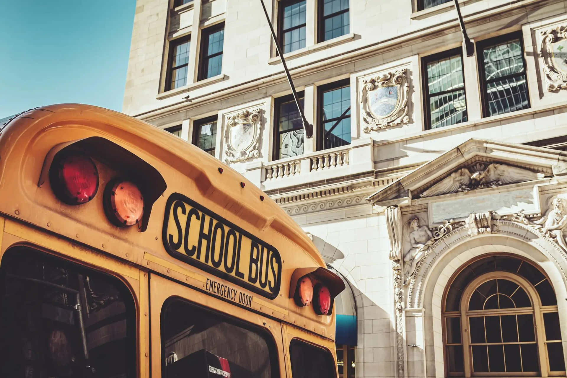 School Bus Outside Classic Building.jpg Wallpaper