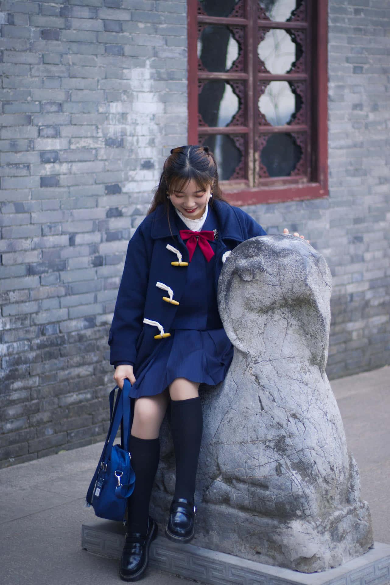 Schoolgirl Smiling Beside Stone Sculpture.jpg Wallpaper