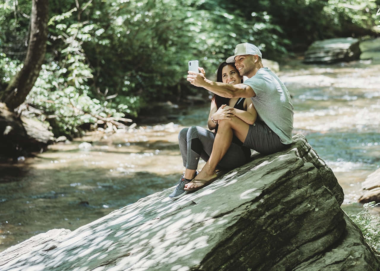 Selfiemann Und Frau In Der Nähe Eines Flusses Wallpaper